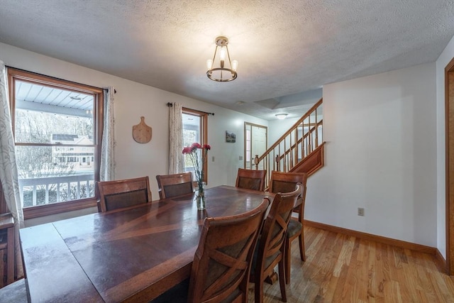 dining room with an inviting chandelier, light hardwood / wood-style flooring, and a textured ceiling