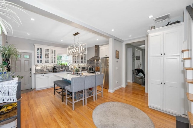 6 Edgehill Rd, Billerica, MA 01862 - kitchen featuring wall chimney range hood, freestanding refrigerator, a kitchen breakfast bar, backsplash, and white cabinets