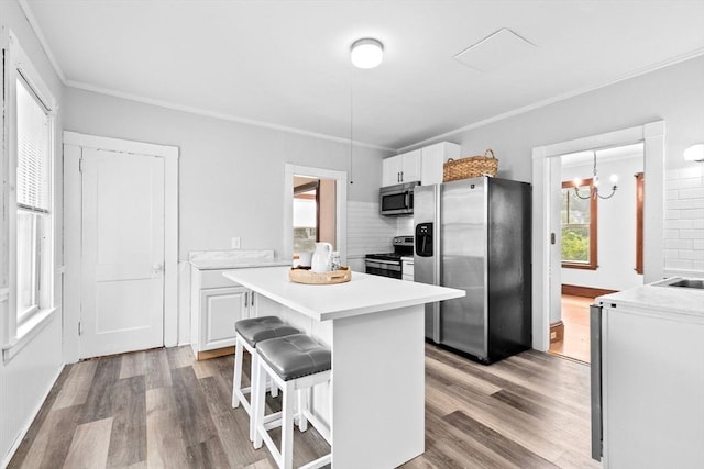 181 Myrtle St, Rockland, MA 02370 - kitchen with stainless steel appliances, white cabinetry, wood finished floors, crown molding, and a center island