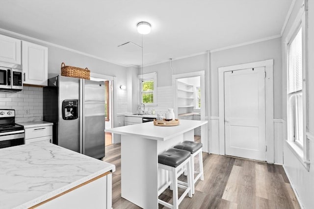 181 Myrtle St, Rockland, MA 02370 - kitchen with stainless steel appliances, tasteful backsplash, white cabinetry, light wood-style floors, and a kitchen bar