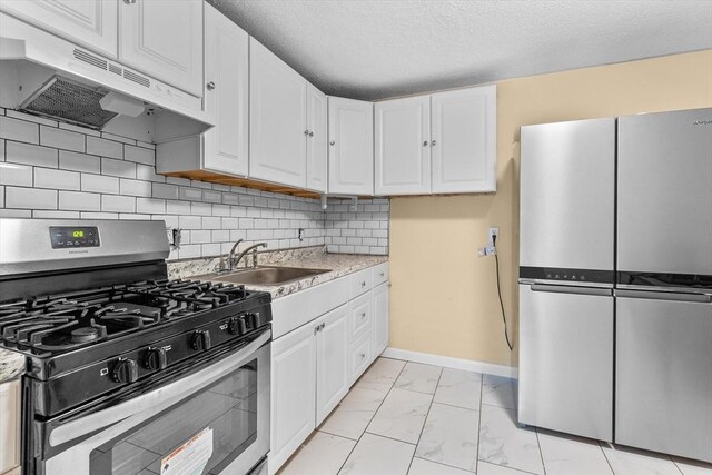 262 E Haverhill St Unit 17, Lawrence, MA 01841 - kitchen with stainless steel appliances, under cabinet range hood, light marble finish flooring, a sink, and white cabinets