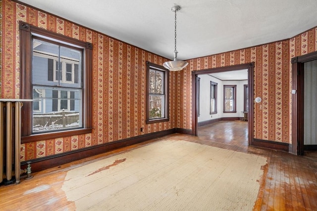 unfurnished dining area featuring plenty of natural light, wood-type flooring, and ornamental molding