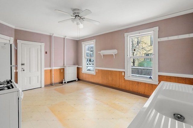 kitchen with radiator heating unit, a wealth of natural light, white appliances, and ornamental molding