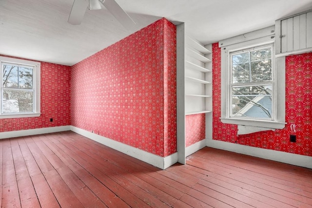 additional living space featuring ceiling fan, wood-type flooring, and built in shelves