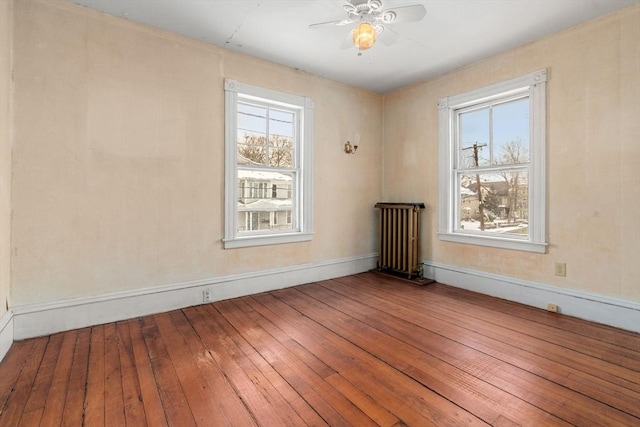 unfurnished room featuring ceiling fan, hardwood / wood-style flooring, and radiator heating unit