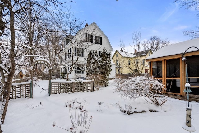 yard layered in snow featuring a sunroom