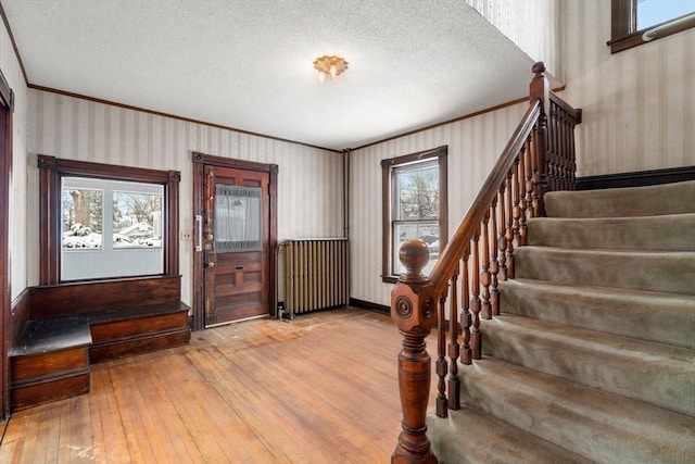 foyer featuring light hardwood / wood-style floors, plenty of natural light, a textured ceiling, and radiator heating unit