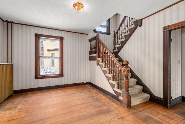 stairway with radiator, a textured ceiling, and hardwood / wood-style floors