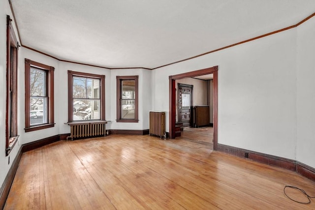 unfurnished room with light hardwood / wood-style floors, radiator heating unit, and crown molding