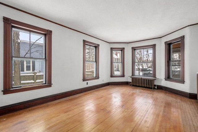 unfurnished room featuring radiator, crown molding, and light wood-type flooring