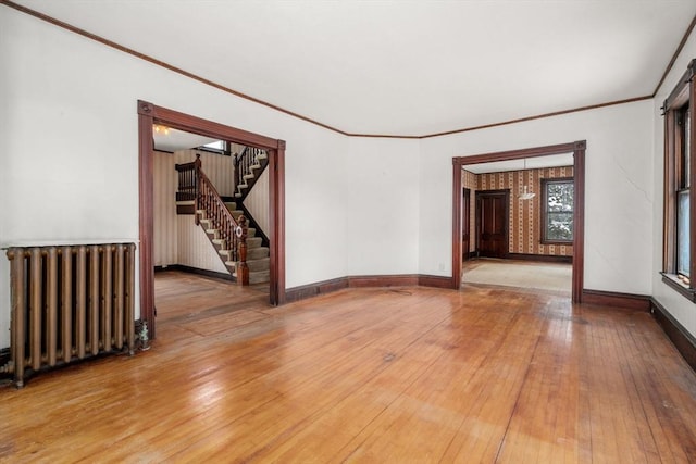 spare room with wood-type flooring, radiator heating unit, and ornamental molding