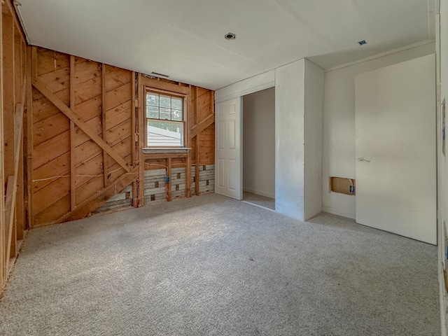 carpeted empty room featuring wooden walls