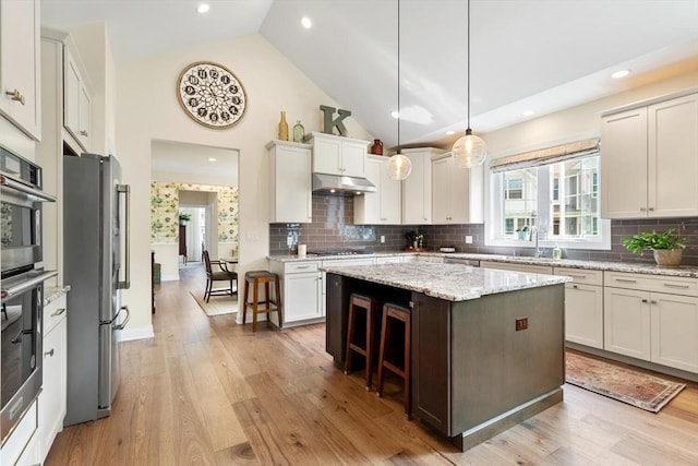 109 Phoebe St Unit 109, Methuen, MA 01844 - kitchen featuring stainless steel appliances, under cabinet range hood, light wood-style floors, a kitchen island, and a breakfast bar