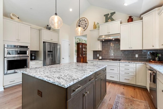 109 Phoebe St Unit 109, Methuen, MA 01844 - kitchen featuring appliances with stainless steel finishes, under cabinet range hood, vaulted ceiling, tasteful backsplash, and pendant lighting