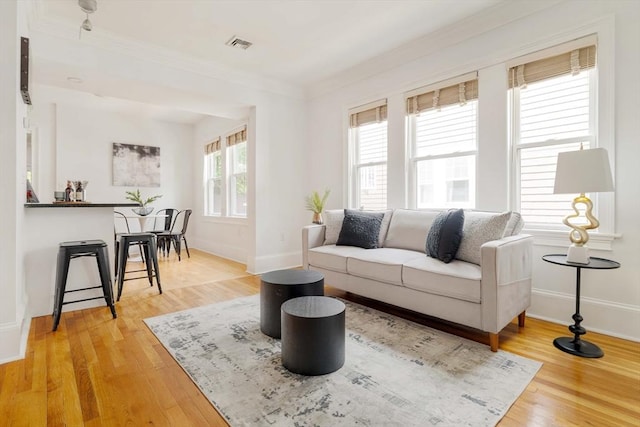 living room featuring ornamental molding, baseboards, and wood finished floors