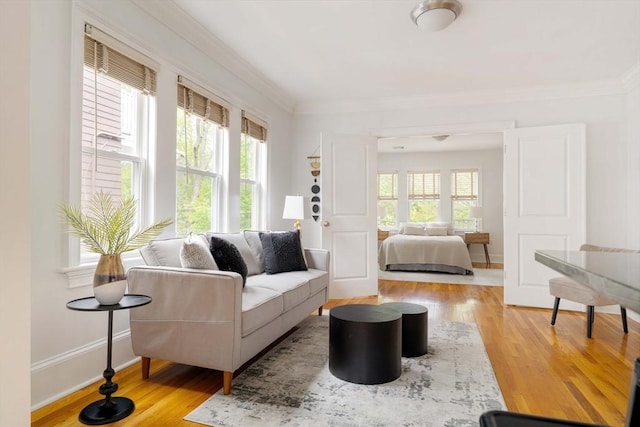 living room featuring healthy amount of natural light, wood finished floors, ornamental molding, and baseboards