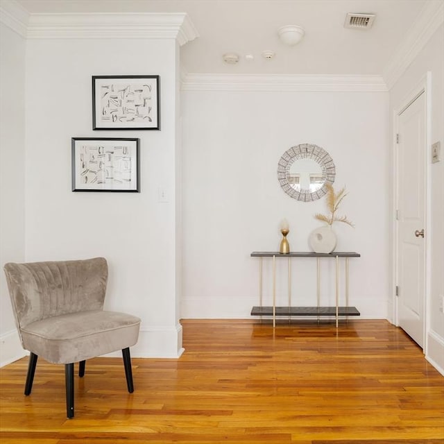 sitting room featuring wood finished floors, ornamental molding, and baseboards