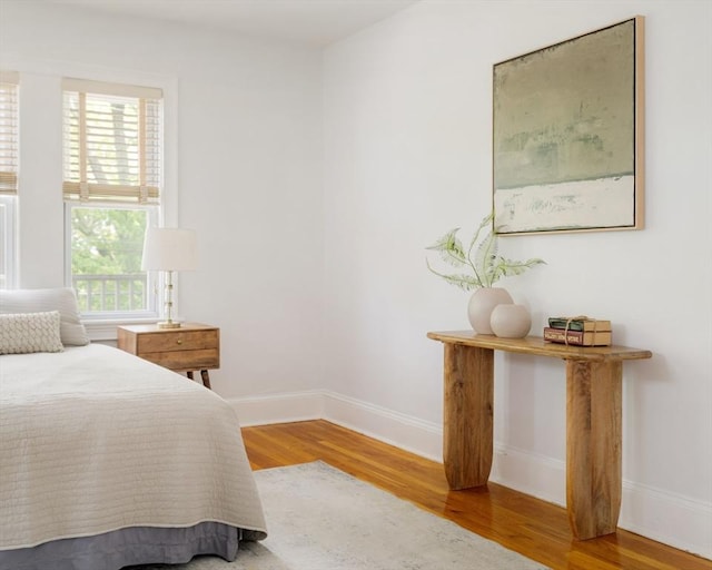 bedroom with wood finished floors, multiple windows, and baseboards