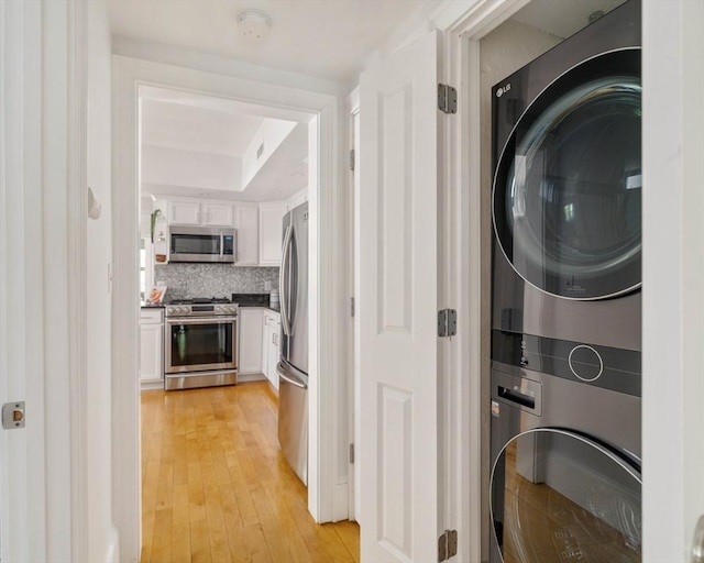 washroom with stacked washer / dryer and light wood-style flooring