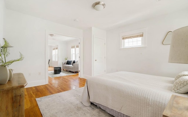 bedroom featuring multiple windows, wood finished floors, and baseboards