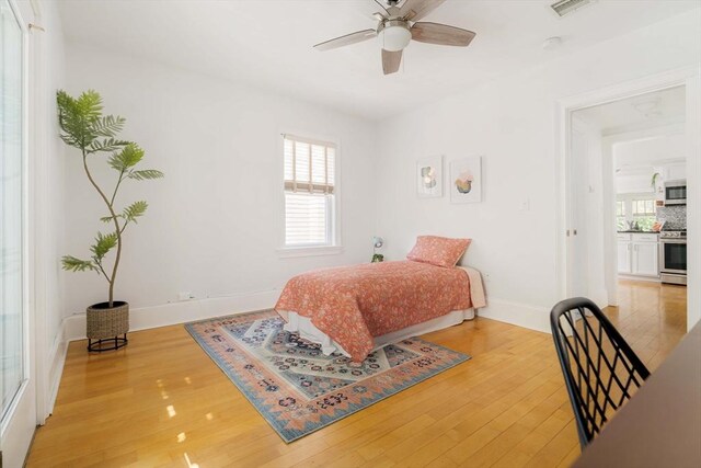 bedroom with light wood-style flooring, baseboards, and a ceiling fan