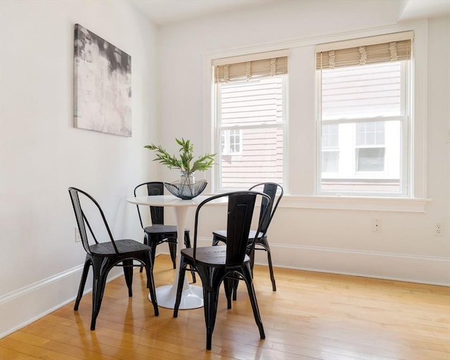 dining room featuring light wood-style flooring, plenty of natural light, and baseboards