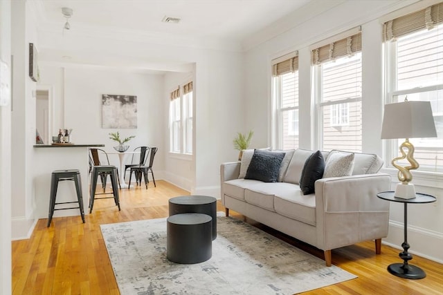 living room featuring plenty of natural light, wood finished floors, crown molding, and baseboards