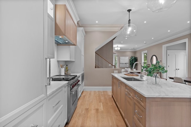 kitchen featuring white cabinetry, a center island with sink, sink, and hanging light fixtures