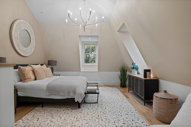 bedroom with light wood-type flooring, vaulted ceiling, and an inviting chandelier