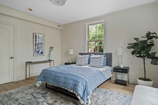 bedroom with crown molding and light hardwood / wood-style floors