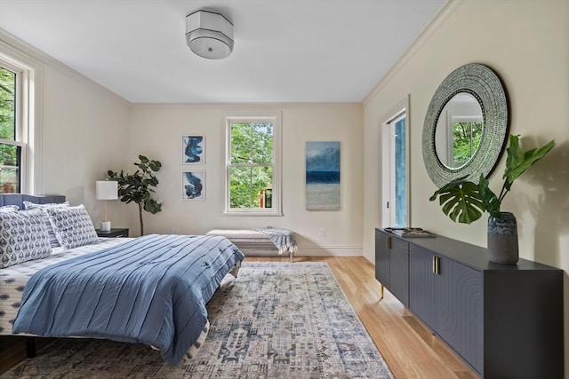 bedroom featuring ornamental molding, multiple windows, and light hardwood / wood-style floors