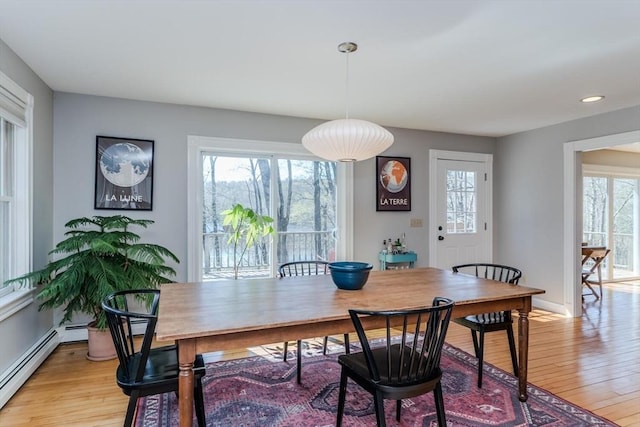 dining area with baseboards, a baseboard heating unit, and light wood-type flooring