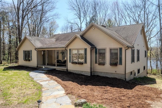 view of front of home featuring a porch, roof with shingles, and a front yard