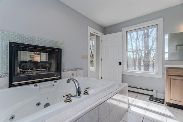 bathroom with a whirlpool tub, a baseboard radiator, a tiled fireplace, and a healthy amount of sunlight