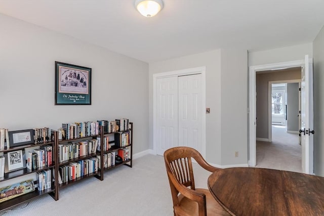 sitting room with a baseboard heating unit, baseboards, and light colored carpet