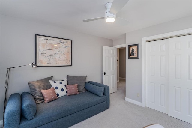 living room with baseboards, a ceiling fan, and light colored carpet
