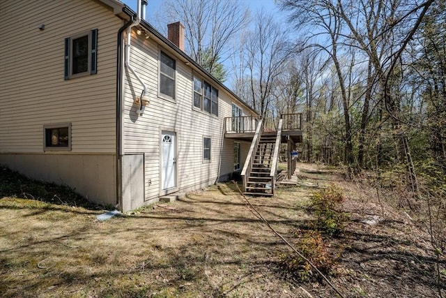 view of side of property featuring a chimney, stairs, and a wooden deck