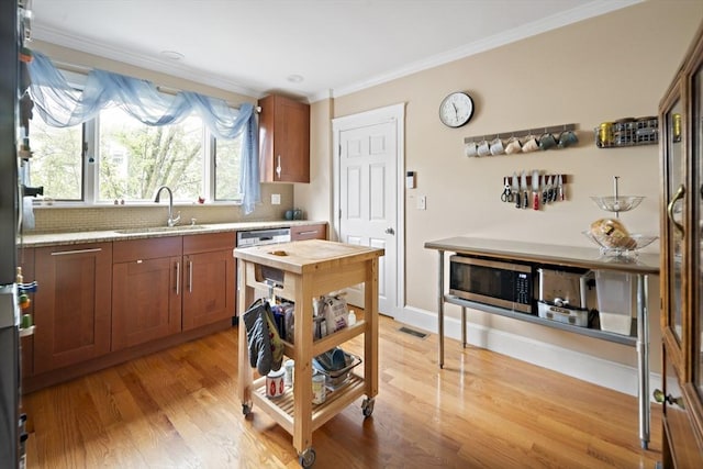 17 Eliot St Unit 17, Medford, MA 02155 - kitchen with stainless steel appliances, brown cabinets, ornamental molding, light wood-style floors, and decorative backsplash
