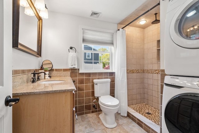 5 Eclipse Ave, Chelmsford, MA 01824 - full bath featuring stacked washing machine and dryer, toilet, tiled shower, vanity, and tile walls