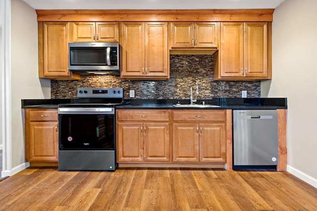 kitchen featuring stainless steel appliances, tasteful backsplash, light hardwood / wood-style floors, and sink