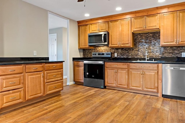 kitchen featuring tasteful backsplash, sink, light hardwood / wood-style floors, and appliances with stainless steel finishes