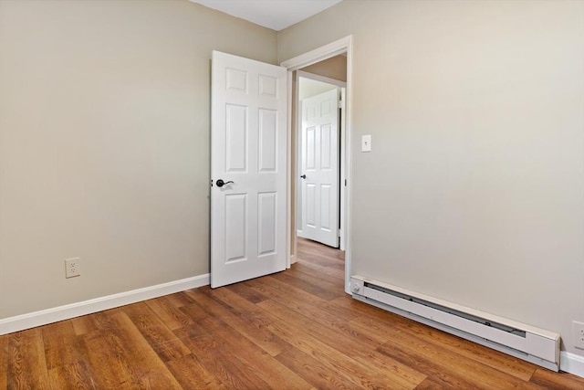 empty room featuring baseboard heating and hardwood / wood-style floors