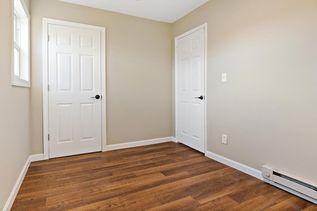 unfurnished bedroom featuring dark wood-type flooring and a baseboard radiator