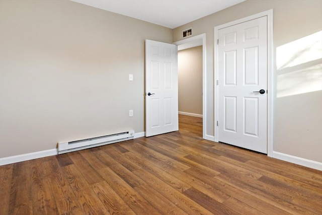 unfurnished bedroom with hardwood / wood-style flooring and baseboard heating