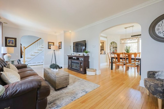 living room with crown molding, arched walkways, stairway, and light wood-style floors