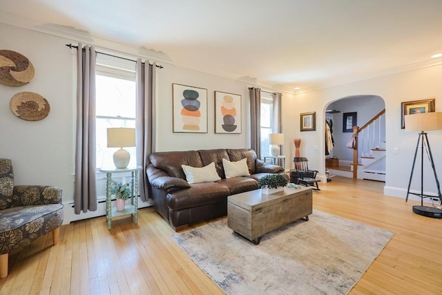 living room featuring arched walkways, stairs, light wood-style flooring, and a wealth of natural light