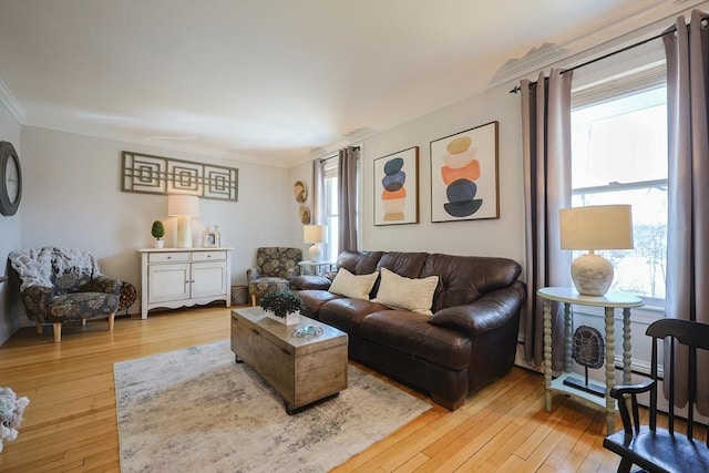 living area with a wealth of natural light, light wood-style floors, and crown molding