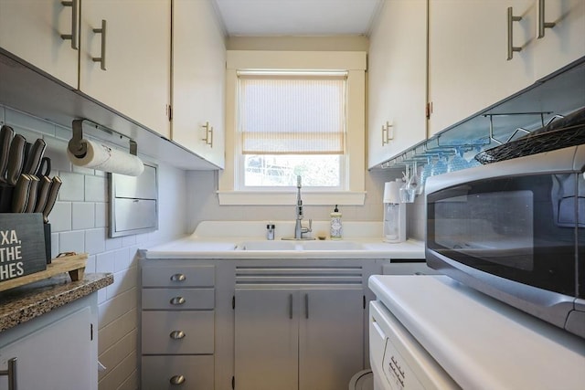 kitchen featuring stainless steel microwave, gray cabinetry, a sink, and white cabinets