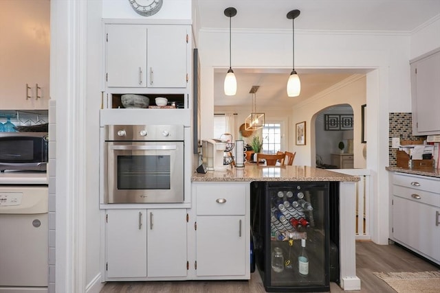 kitchen with white cabinetry, appliances with stainless steel finishes, beverage cooler, ornamental molding, and wood finished floors