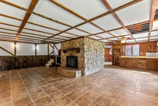 57 Rudon Dr, North Attleboro, MA 02760 - unfurnished living room with wood walls, stairway, ceiling fan, a stone fireplace, and a wainscoted wall